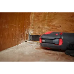 Milwaukee Open-Lok 1-1/4" Titanium Charged Bi-Metal Multi-Material Multi-Tool Blade cutting into the bottom of a wooden wall.