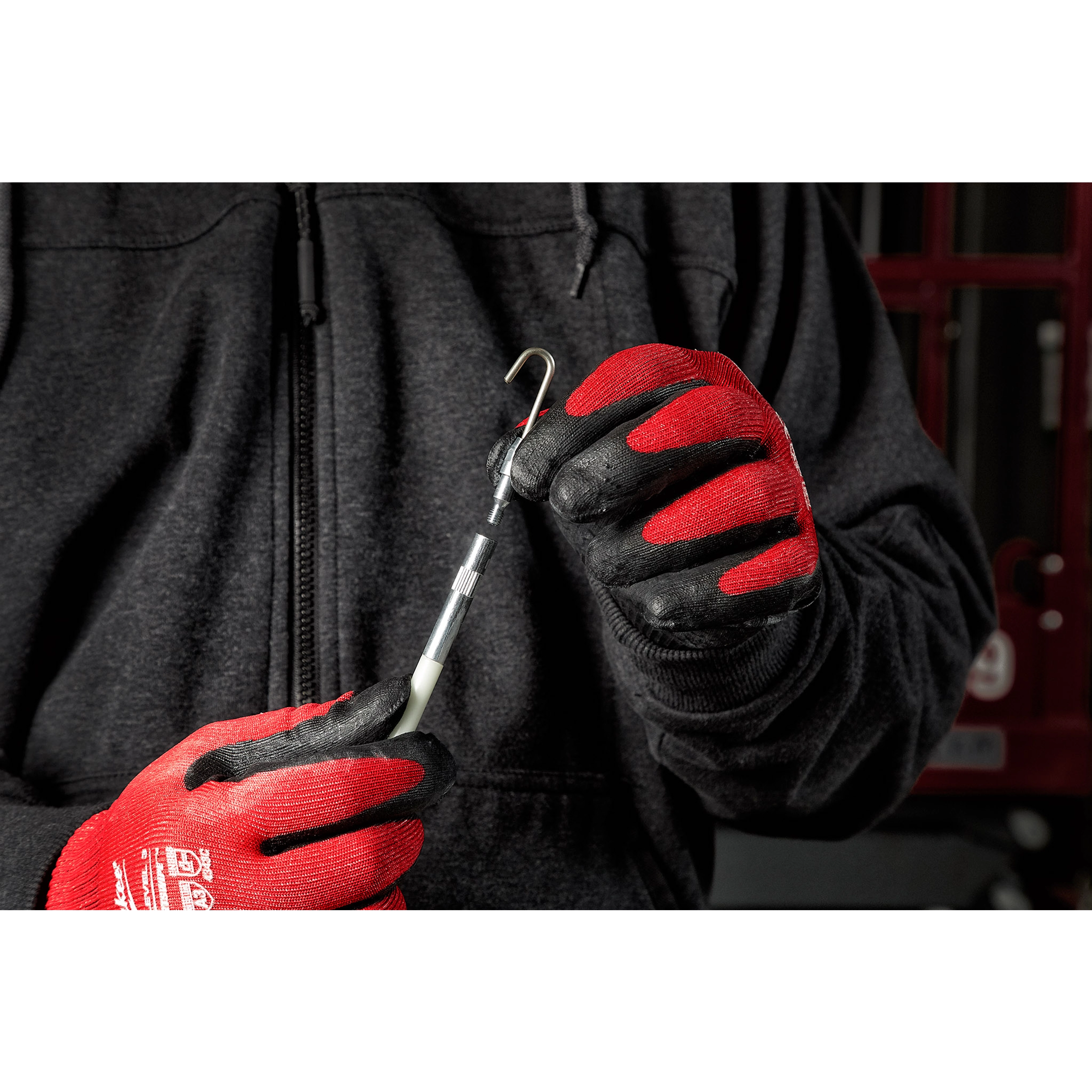 Person wearing red and black gloves holds a green rod tip accessory from the 3pc Fish Stick Tip Accessory Kit against a dark background.