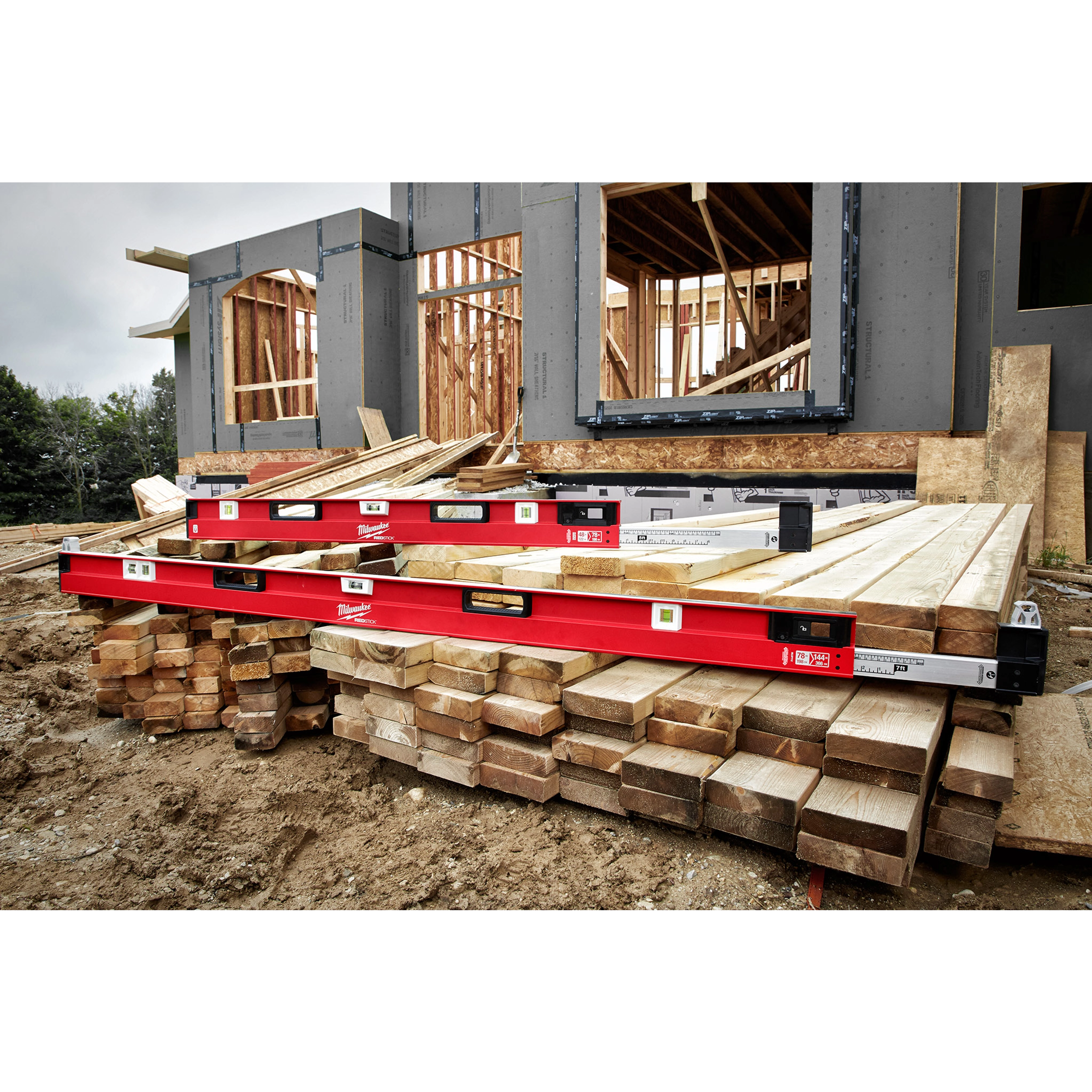 78"-144" Expandable Plate Level placed on wooden beams at a construction site with partially built wooden structures in the background.