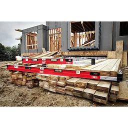 78"-144" Expandable Plate Level placed on wooden beams at a construction site with partially built wooden structures in the background.