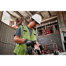 A construction worker operates a power saw while wearing a green safety vest and BOLT White Full Brim Vented Hard Hat w/6pt Ratcheting Suspension.