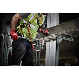 Worker using 10 LB QUICK-CONNECT Locking Tool Lanyard with 10 LB Accessory while wearing safety gear on scaffolding.