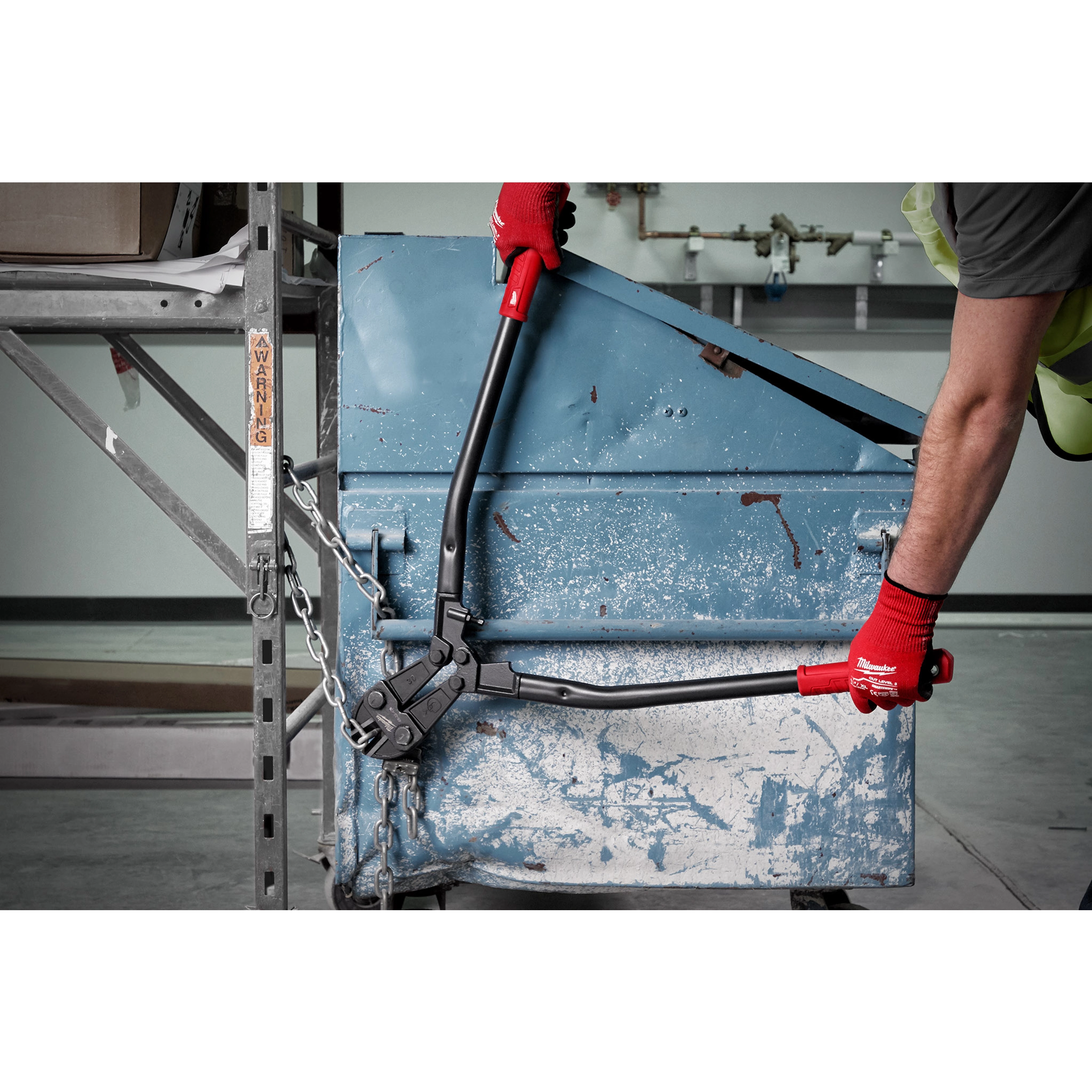 Person using 30" Bolt Cutter with red handles and black blades to cut a thick metal chain securing a blue container.