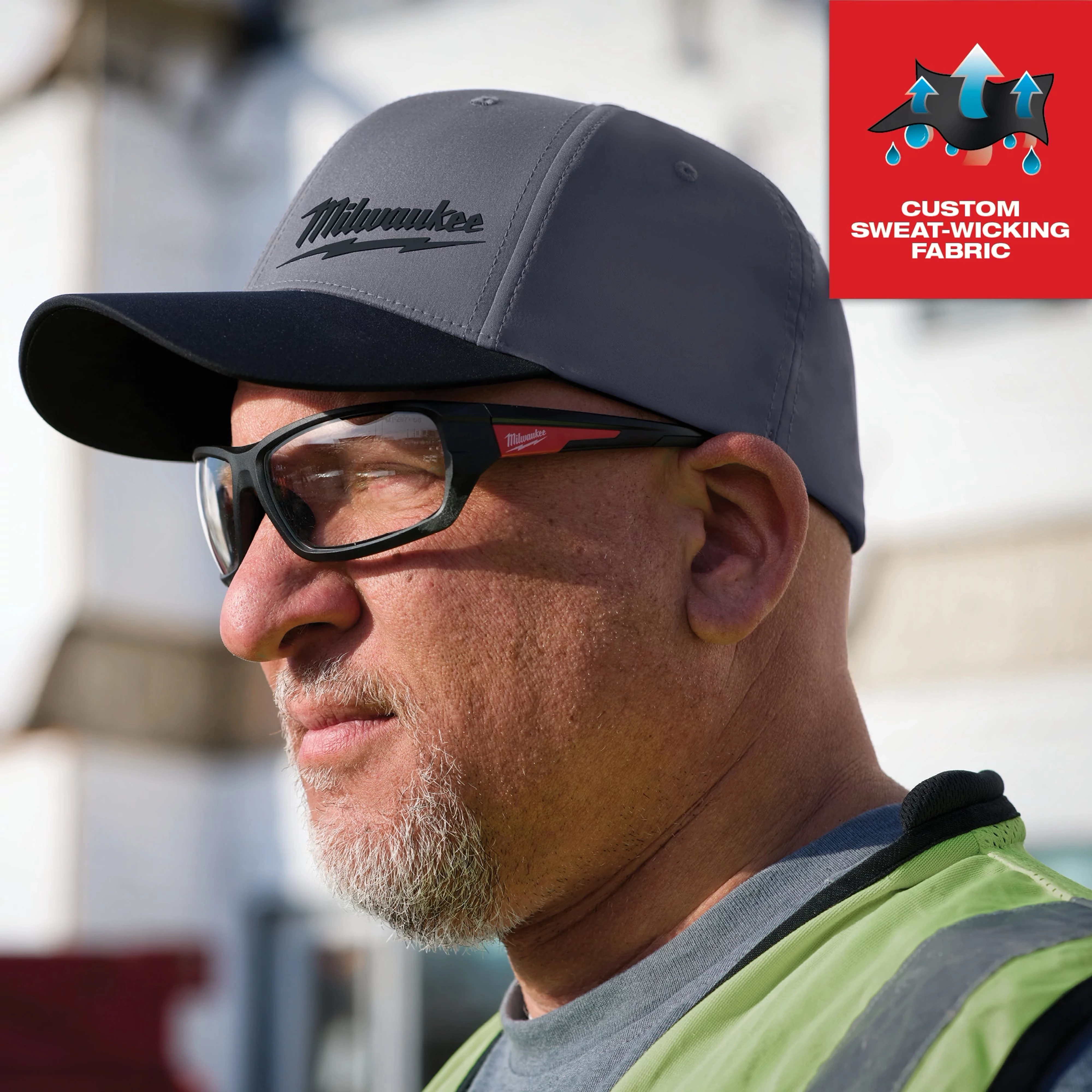 WORKSKIN Performance Fitted Hat in dark gray, custom sweat-wicking fabric, worn by a person in a work environment.