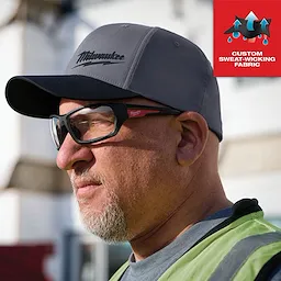 WORKSKIN Performance Fitted Hat in dark gray, custom sweat-wicking fabric, worn by a person in a work environment.