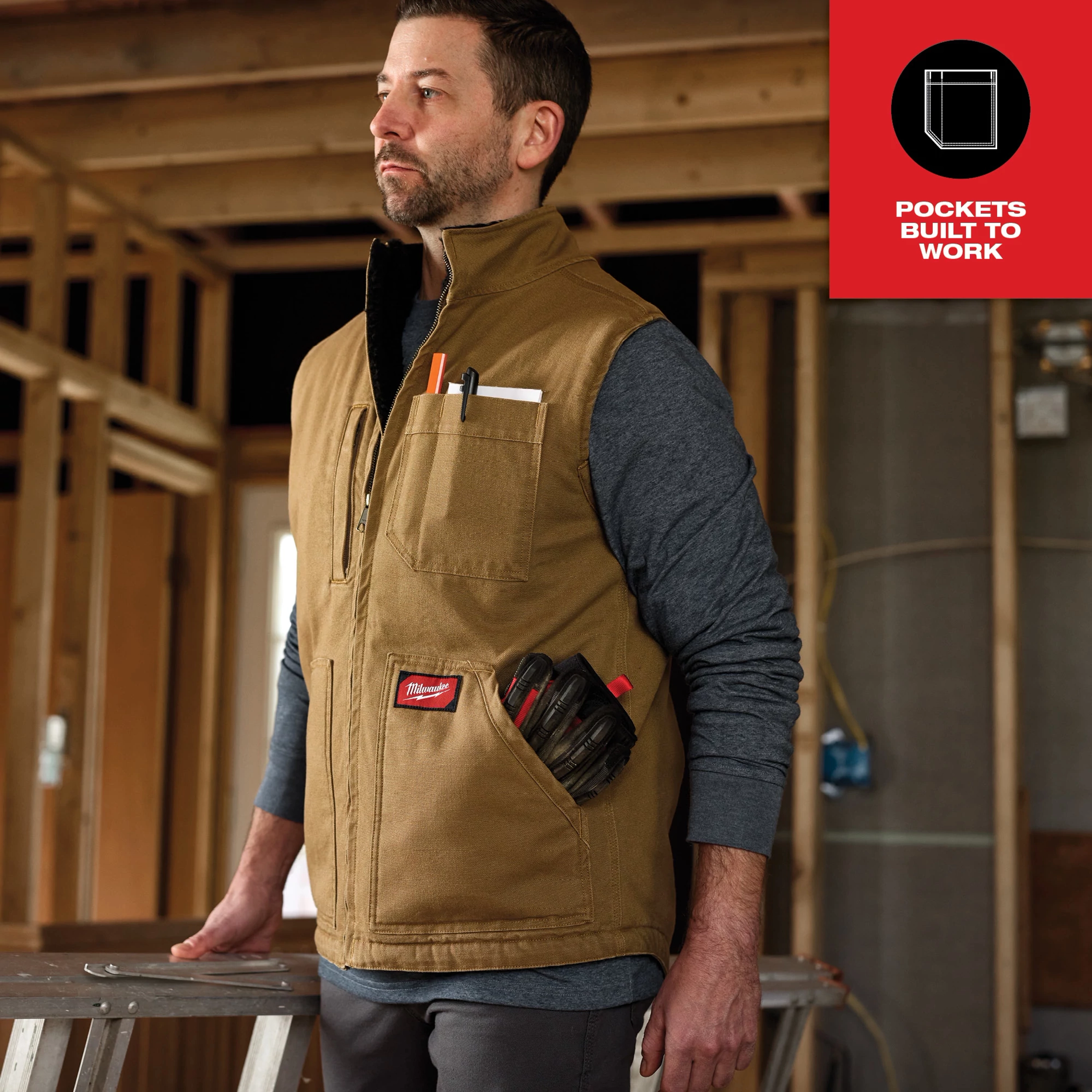 Heavy Duty Sherpa-Lined Vest Feature Shot in a construction setting, worn over a grey long-sleeve shirt, with tools in the pockets.