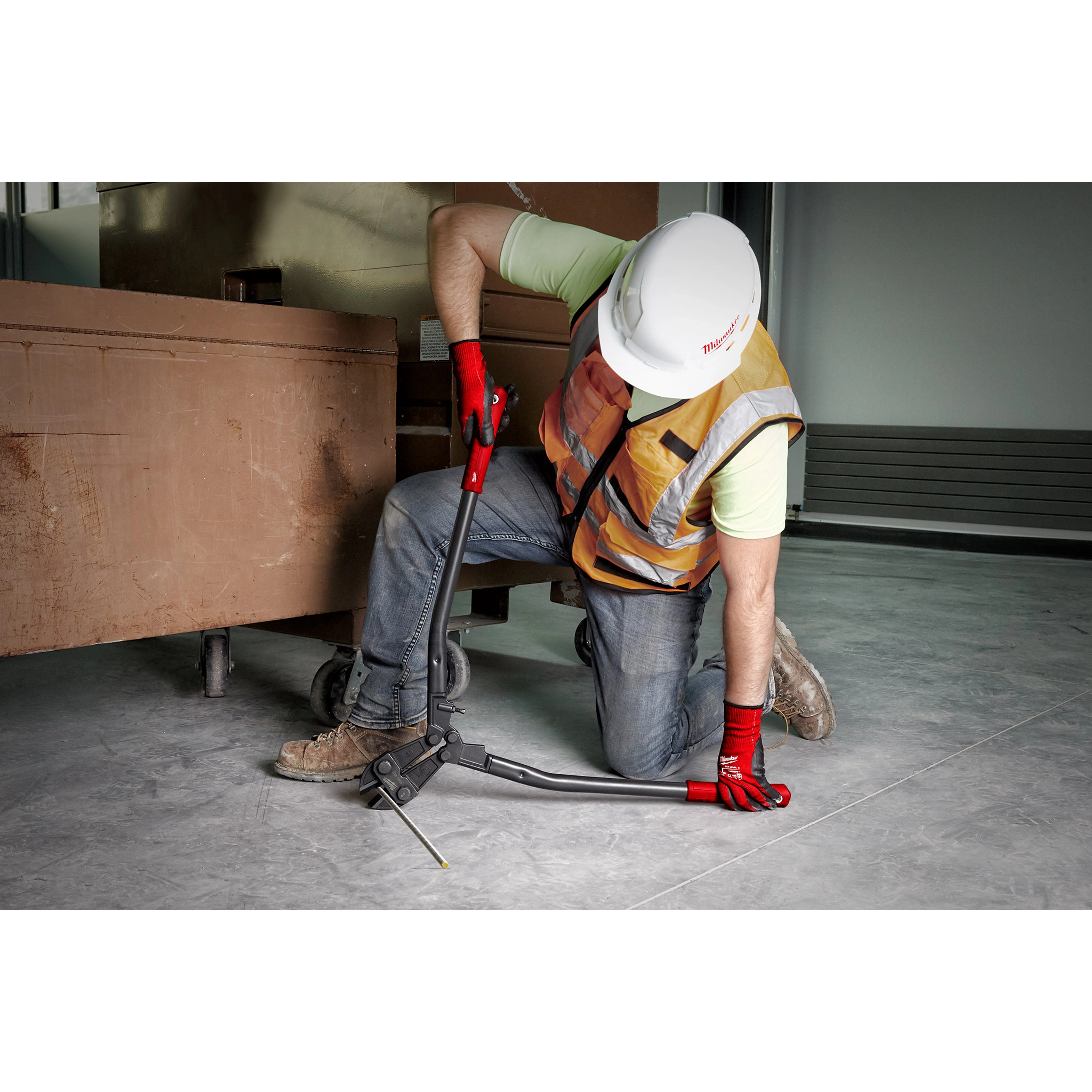 Worker using a 30" Bolt Cutter to cut a metal rod. The worker wears a hard hat, safety vest, jeans, and red gloves.