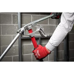 Person wearing red gloves using a 3/4" EMT Aluminum Conduit Bender to bend an electrical conduit in an unfinished room.