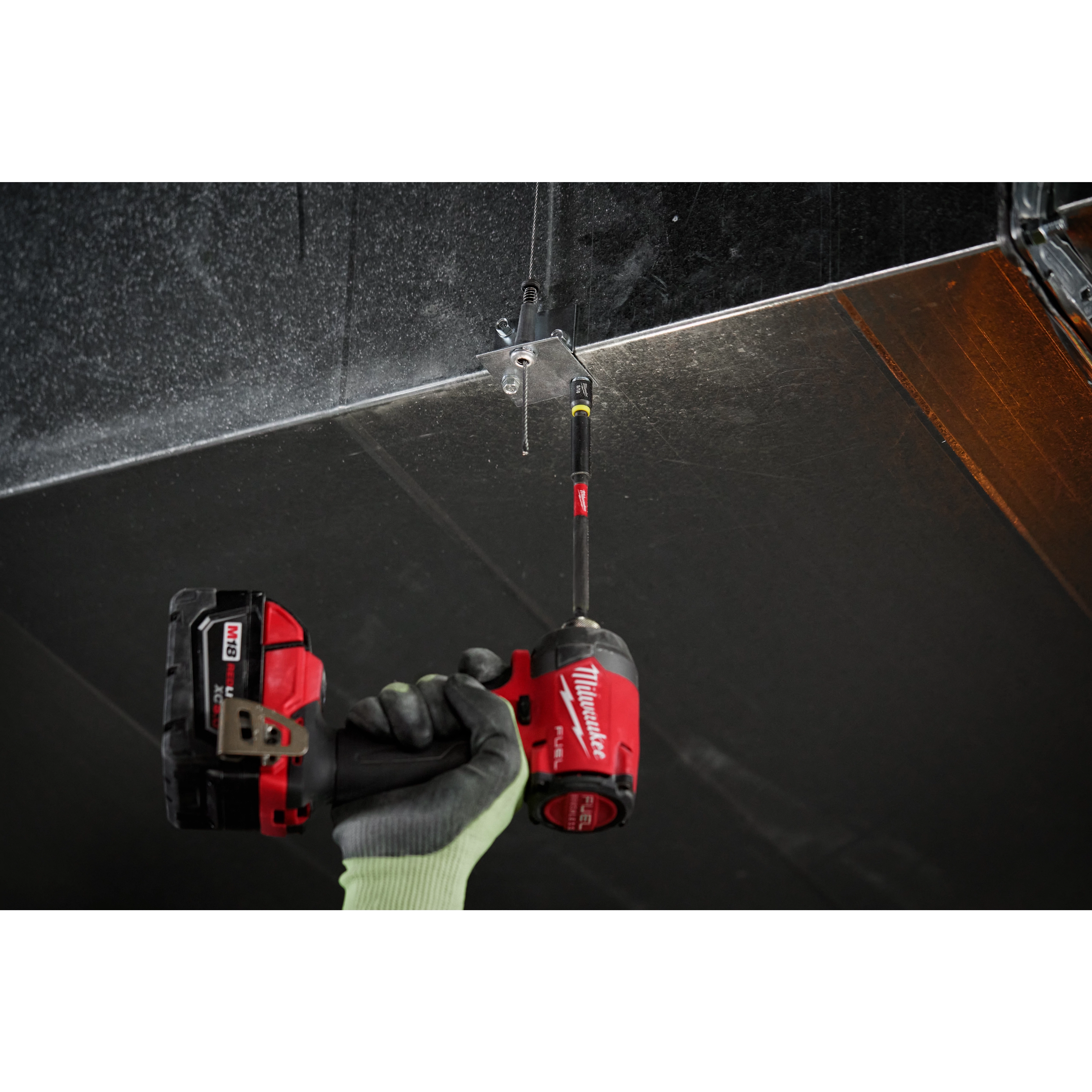 Person using a red power drill equipped with the SHOCKWAVE Impact Duty 5/16” Insert Magnetic Nut Driver 3PK to secure a metal plate.