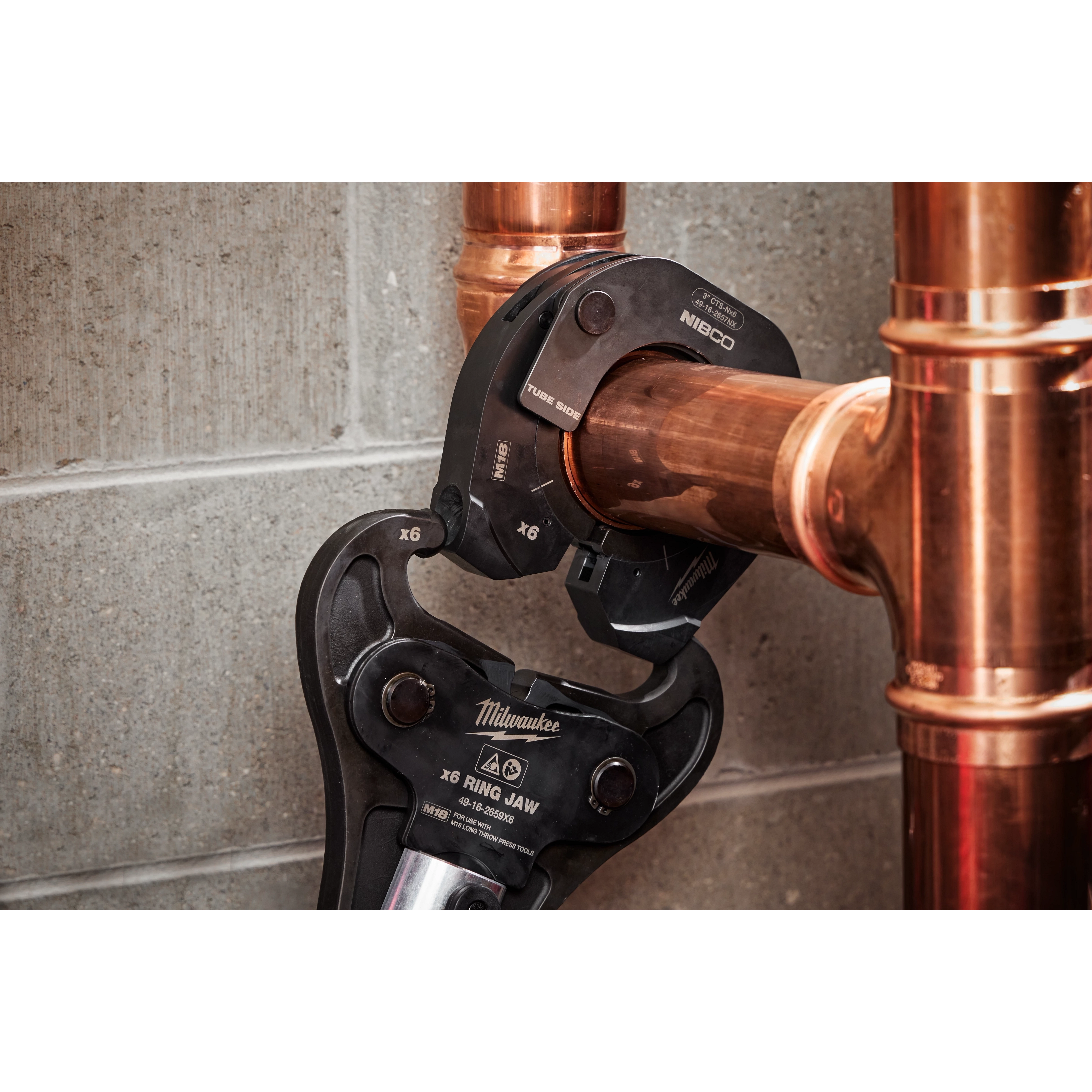 3" NIBCO Press Ring connected to an M18 FORCE LOGIC Long Throw Press Tool, securing copper pipes against a concrete wall.