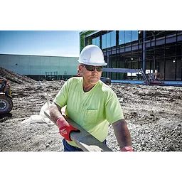 A construction worker wearing Safety Glasses - Tinted Anti-Scratch Lenses, a white hard hat, and red gloves holding a wooden plank.
