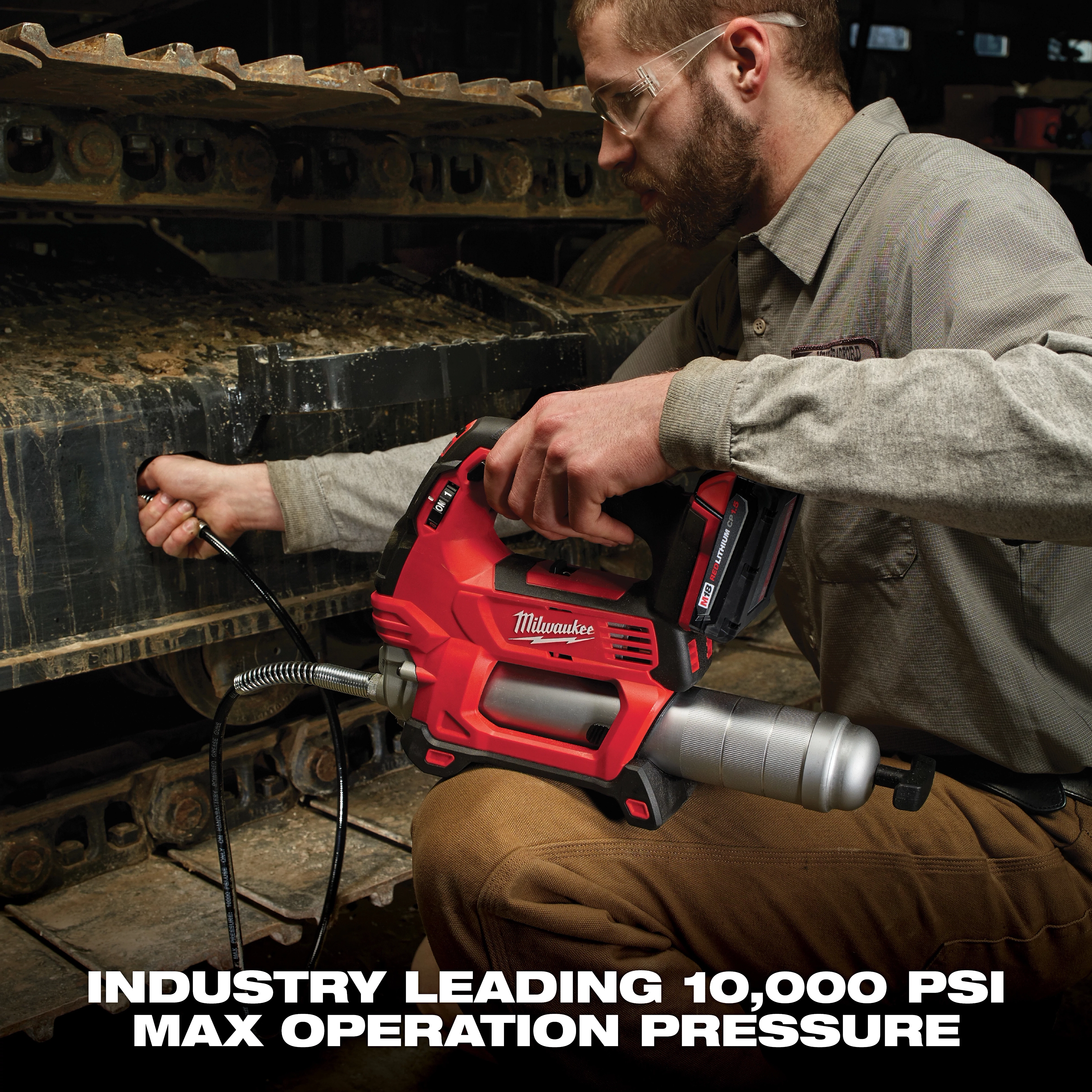 A person operates a red Milwaukee power tool designed for industrial use on heavy machinery, featuring a max operation pressure of 10,000 PSI.