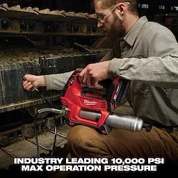 A person operates a red Milwaukee power tool designed for industrial use on heavy machinery, featuring a max operation pressure of 10,000 PSI.