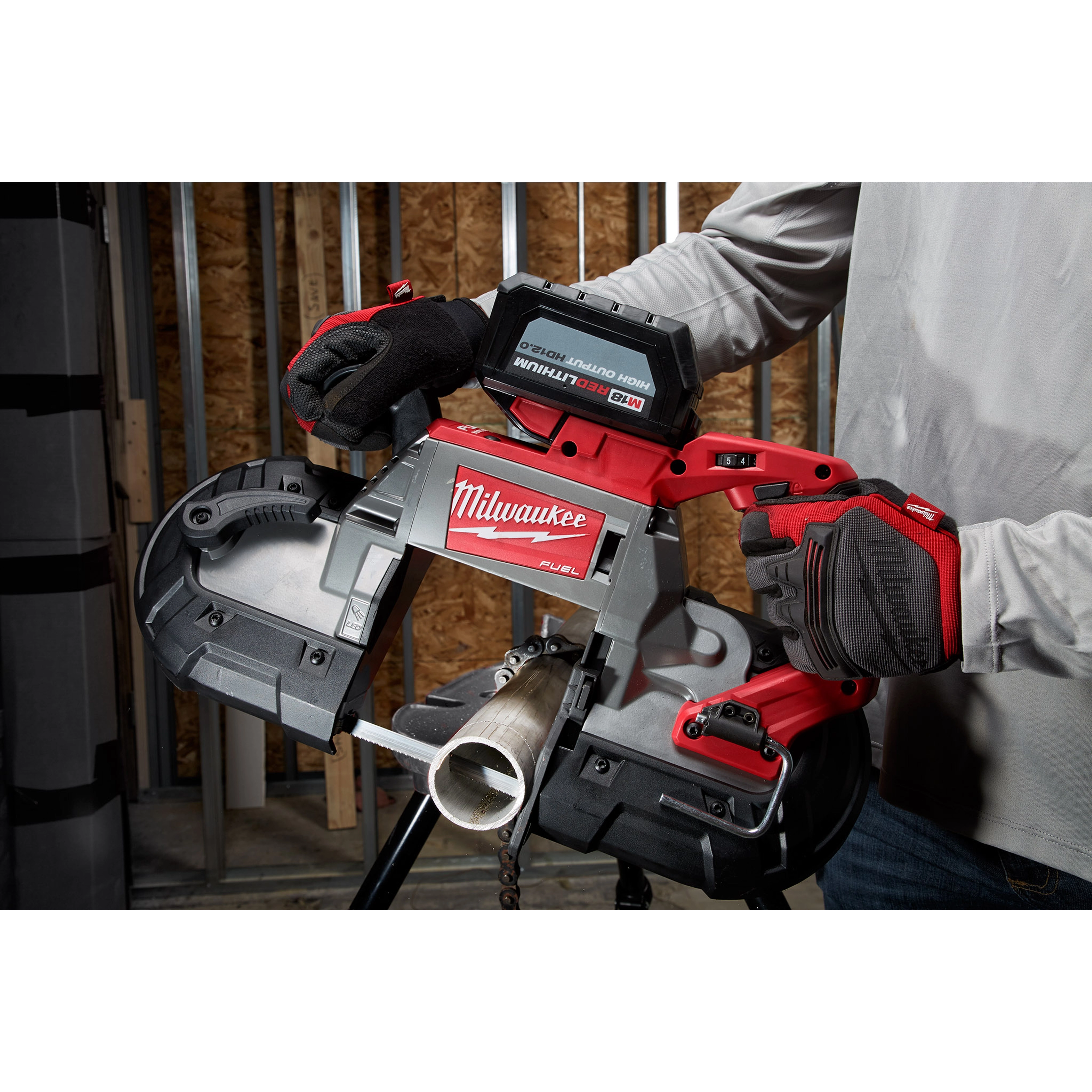 A person using a Milwaukee deep cut extreme thin band saw blade to cut a metal pipe, with the focus on the tool and blade.
