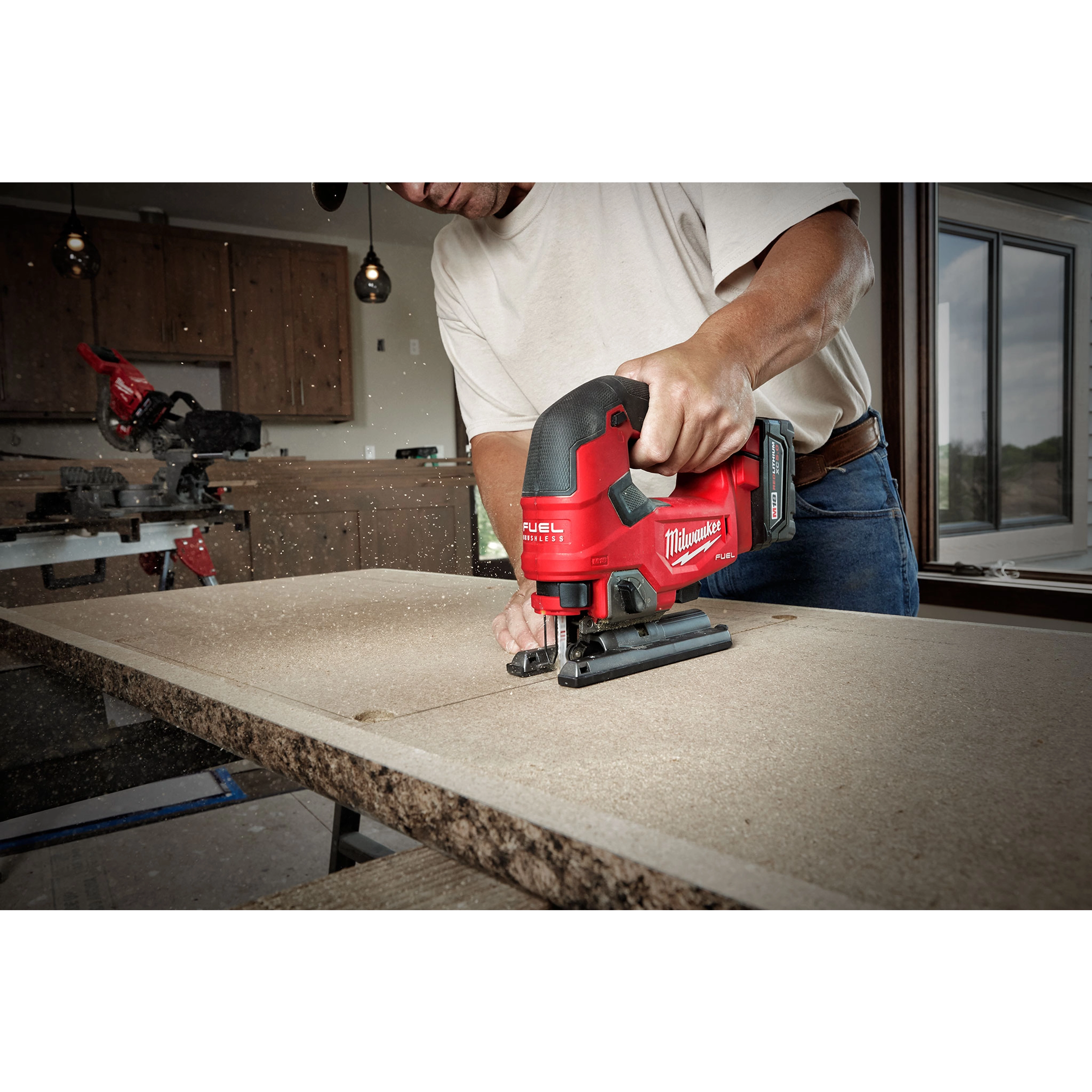 A person in a white shirt uses the M18 FUEL Jigsaw, D-Handle to cut through a piece of wood in a workshop setting.