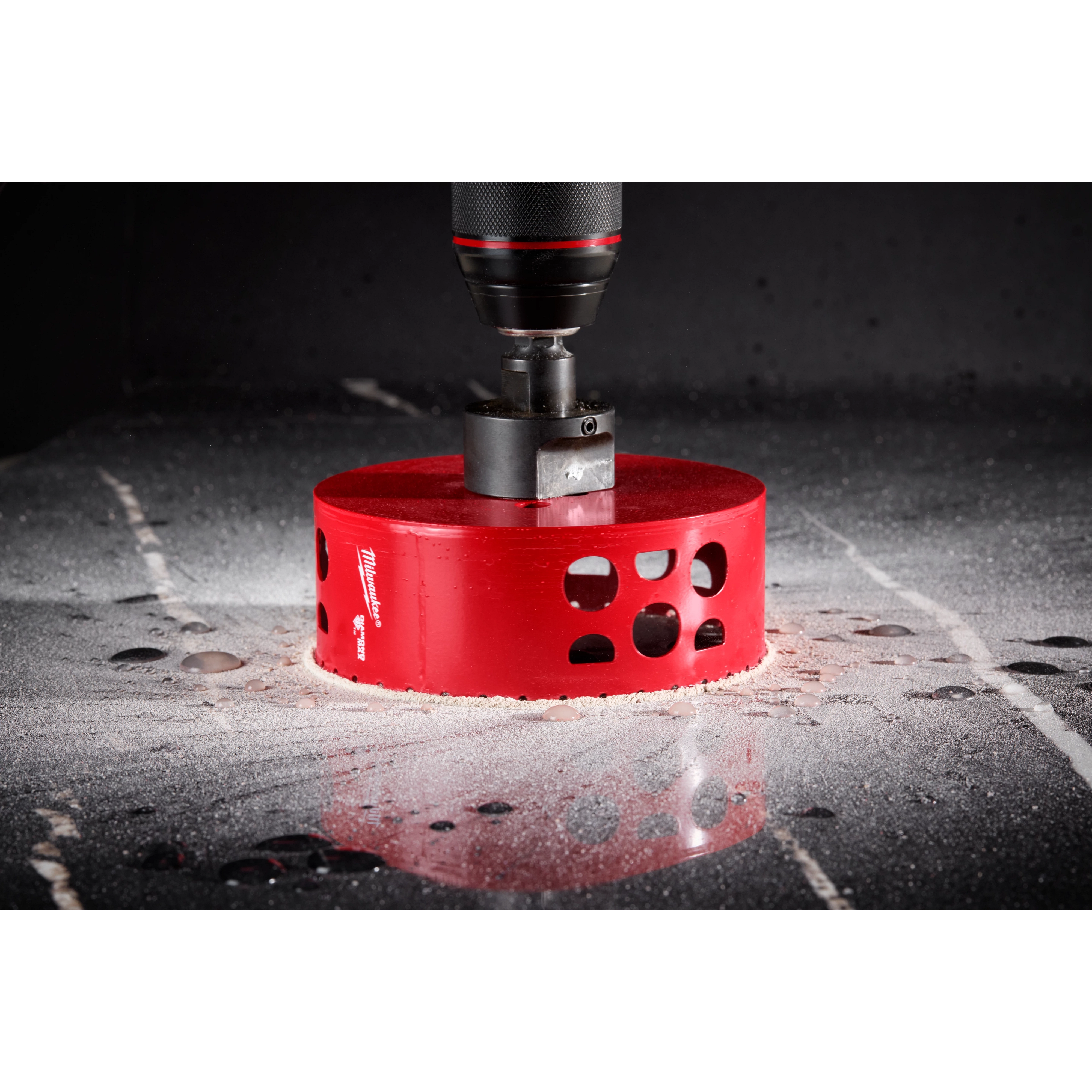 A close-up image of a Milwaukee® 4-1/2" DIAMOND MAX™ Hole Saw, shown cutting through a smooth, reflective surface. The bright red hole saw is attached to a drill, and there is dust and fragments around the cutting area.