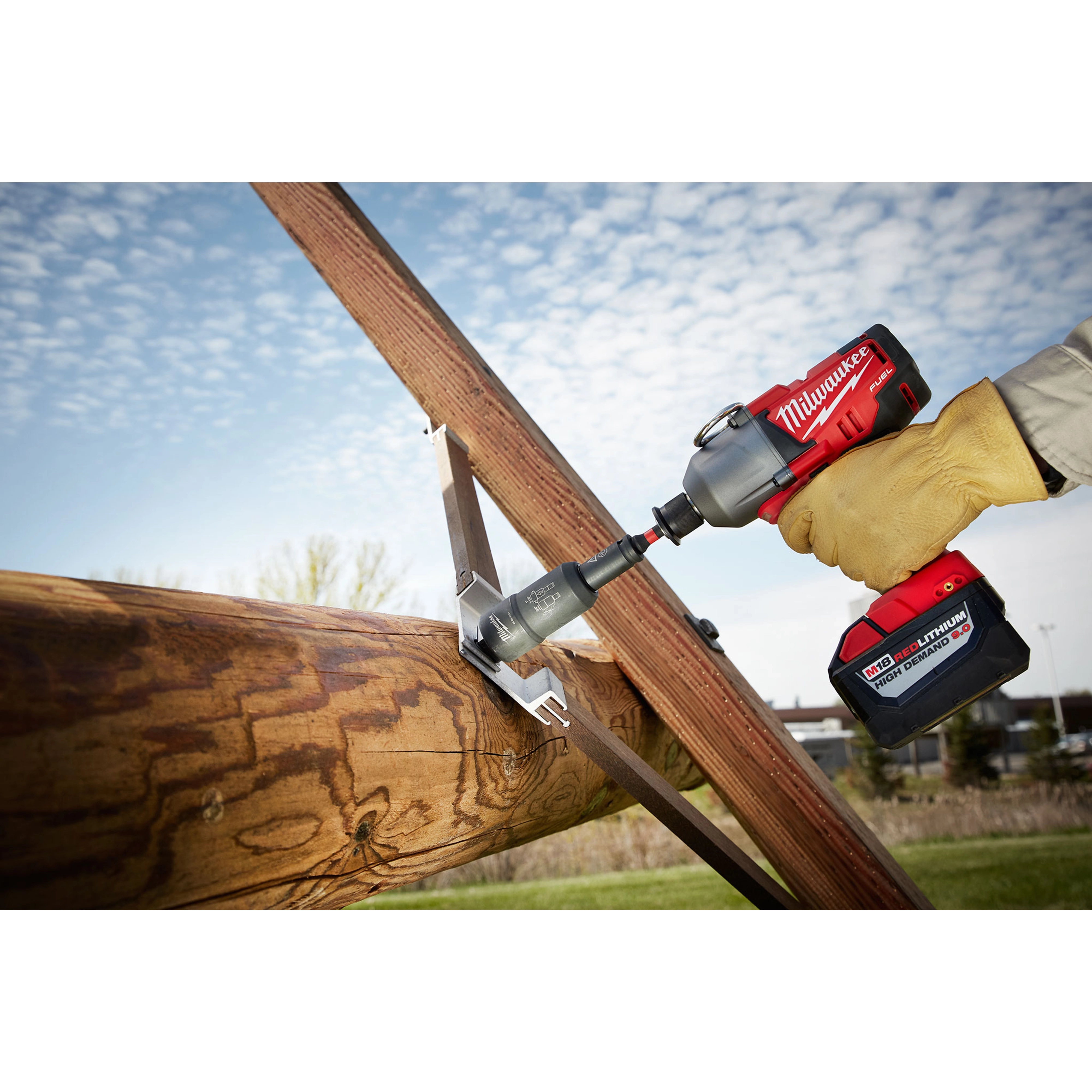 Power Utility Socket being used with a cordless power drill to tighten a bolt on a wooden structure outdoors under a blue sky.