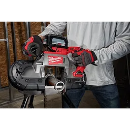 Technician cutting a metal pipe using a Deep Cut Thick Band Saw Blade on a red and silver Milwaukee portable band saw.