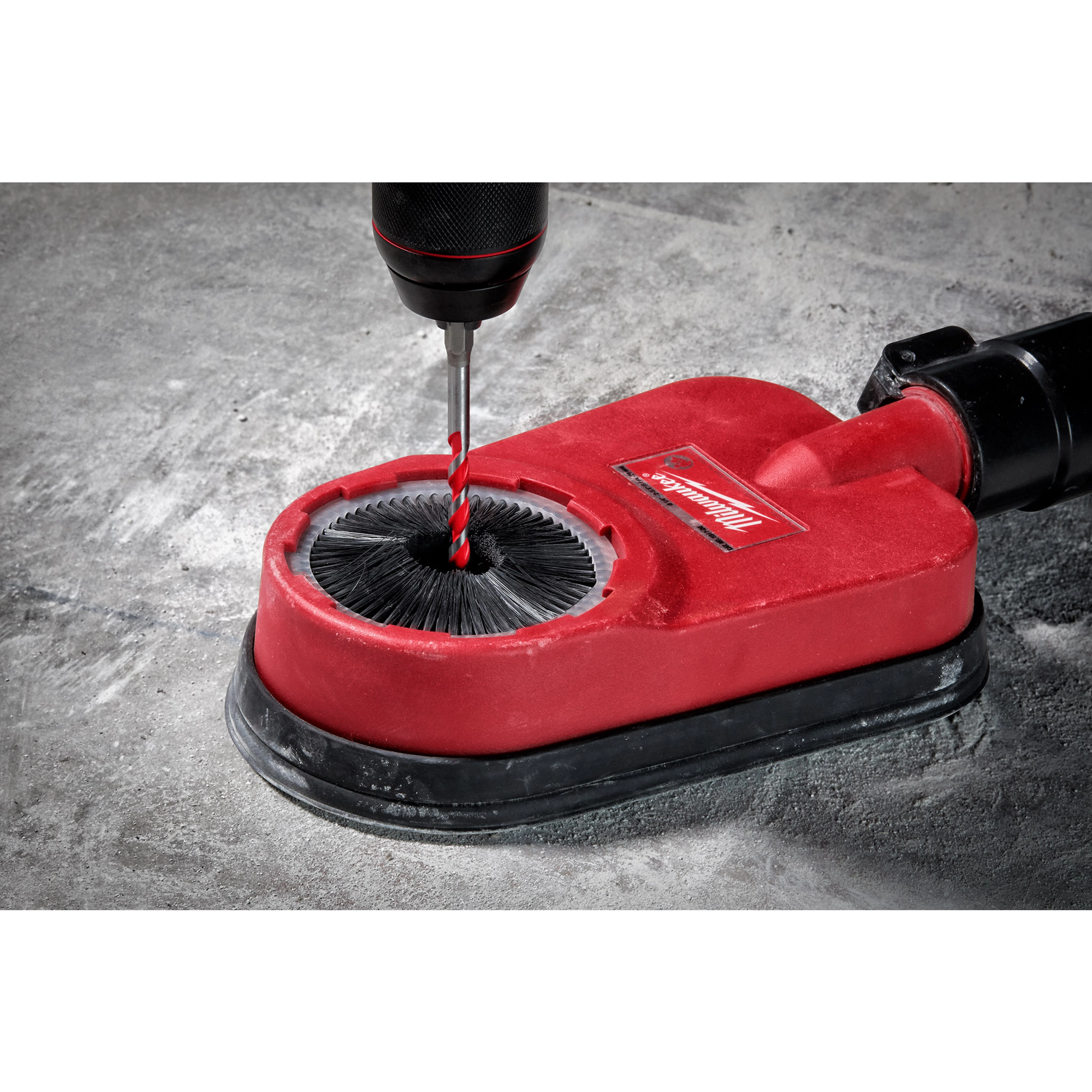 Hammer drill in use with 1/4" x 4" x 6" Hammer Drill Bit, drilling into concrete with a red dust extraction attachment.