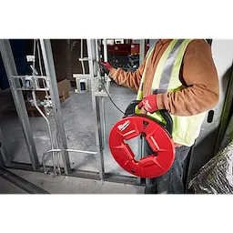 Worker using 200% Polyester Fish Tape with Non-conductive tip in a construction setting, wearing a yellow vest and red gloves.