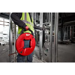 Person wearing gloves and a safety vest holds a red 200% Polyester Fish Tape with Flexible Leader in a construction setting.