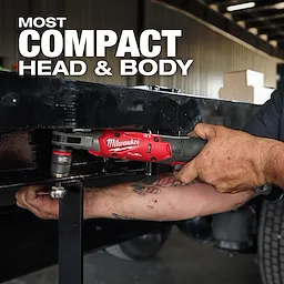 A person operates the M12 FUEL™ 1/2" Ratchet on a black metal frame in an industrial setting. The text "MOST COMPACT HEAD & BODY" is displayed above the tool.