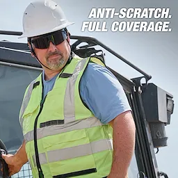 Person wearing high-visibility vest, hard hat, and Wrap Around Safety Glasses - Tinted Anti-Scratch Lenses with text "ANTI-SCRATCH. FULL COVERAGE."