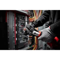 Person using the 750 MCM Cu/Al Cutting Jaw tool to cut a copper wire inside an electrical panel, with colorful cables in the background.