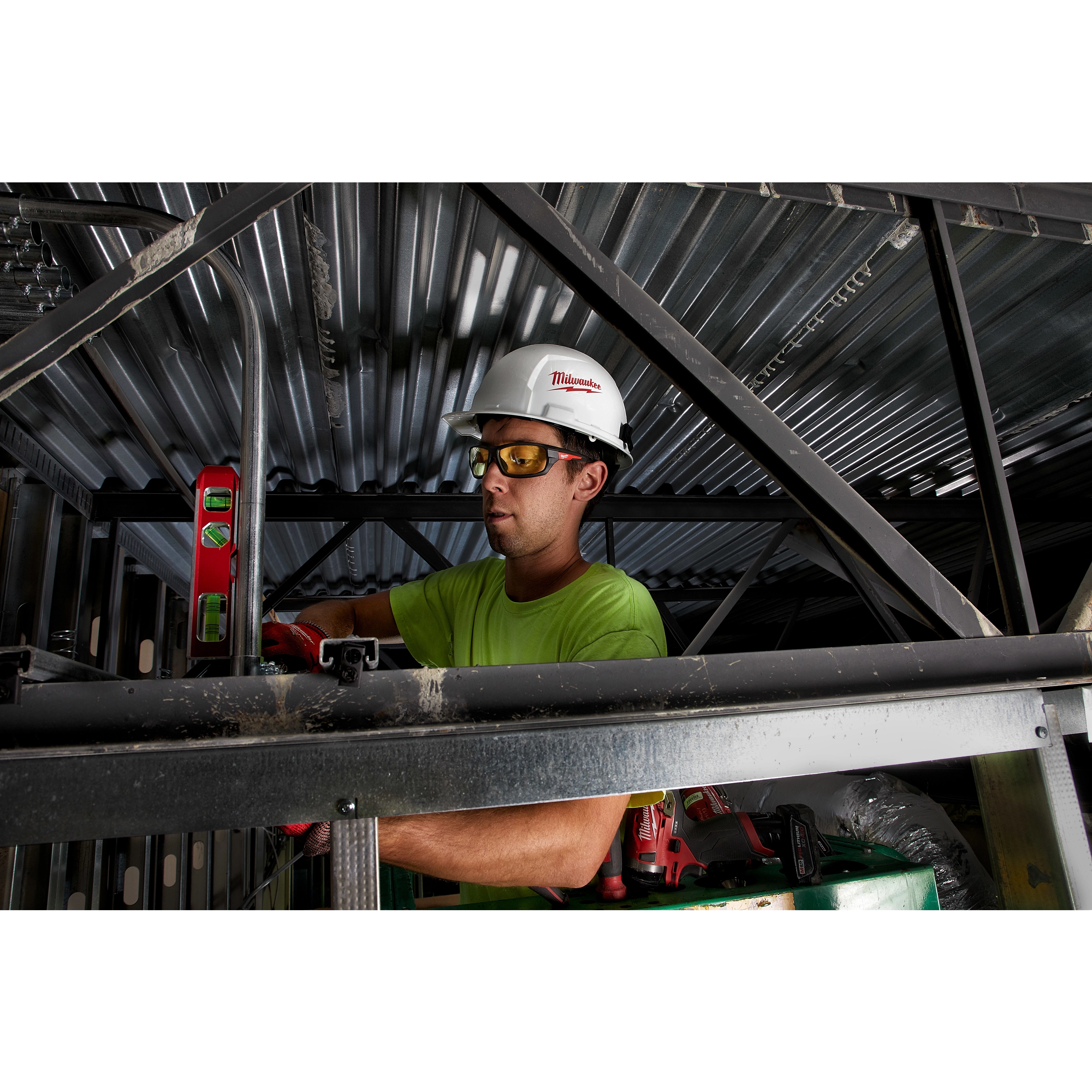 Worker wearing Performance Safety Glasses - Yellow Fog-Free Lenses, protective helmet, and gloves while using a level tool in construction.