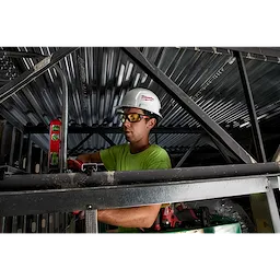 Worker wearing Performance Safety Glasses - Yellow Fog-Free Lenses, protective helmet, and gloves while using a level tool in construction.