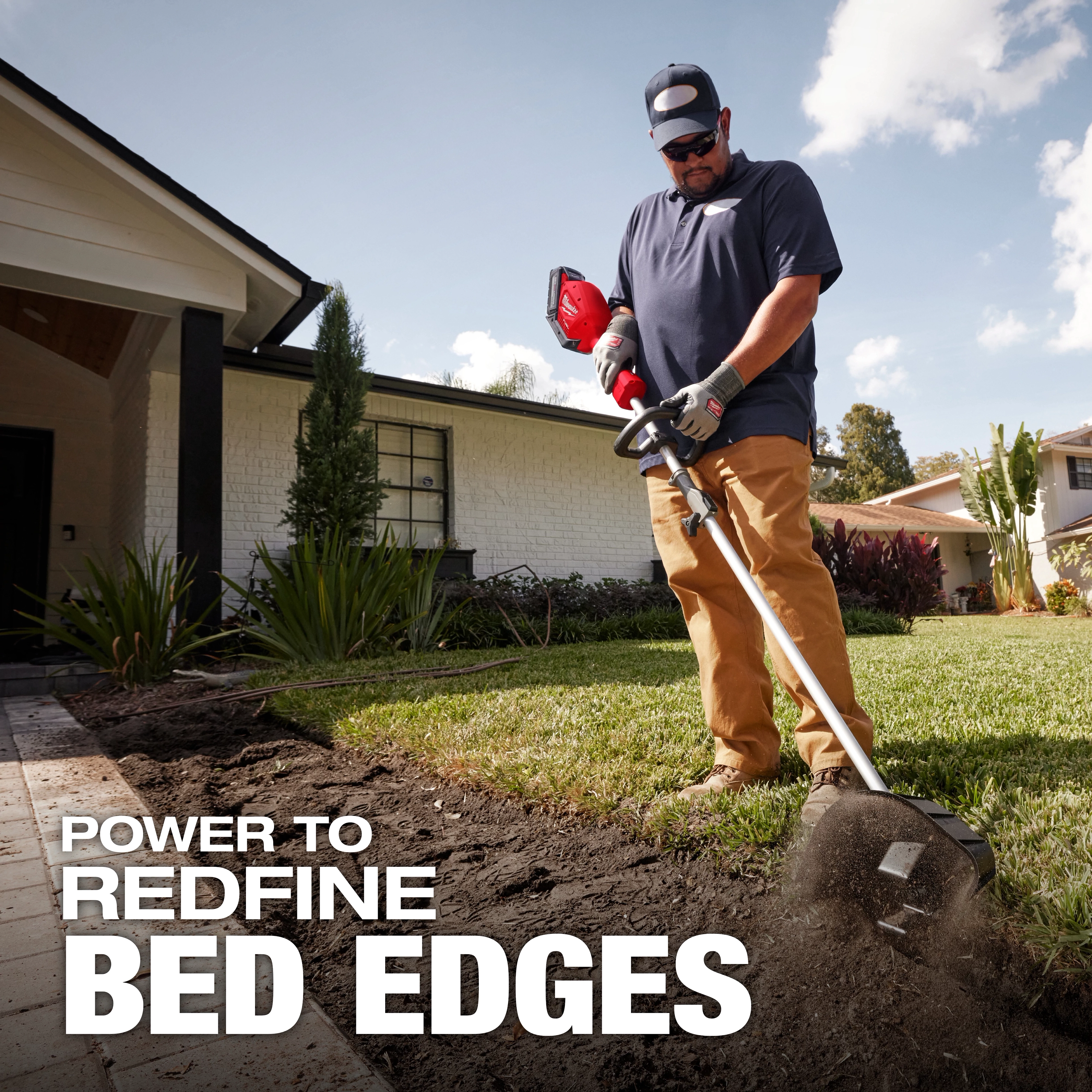 A person is using a power tool to edge a garden bed beside a house with a white exterior. The text overlay reads, "POWER TO REDEFINE BED EDGES." The tool is kicking up soil while creating a neat border.