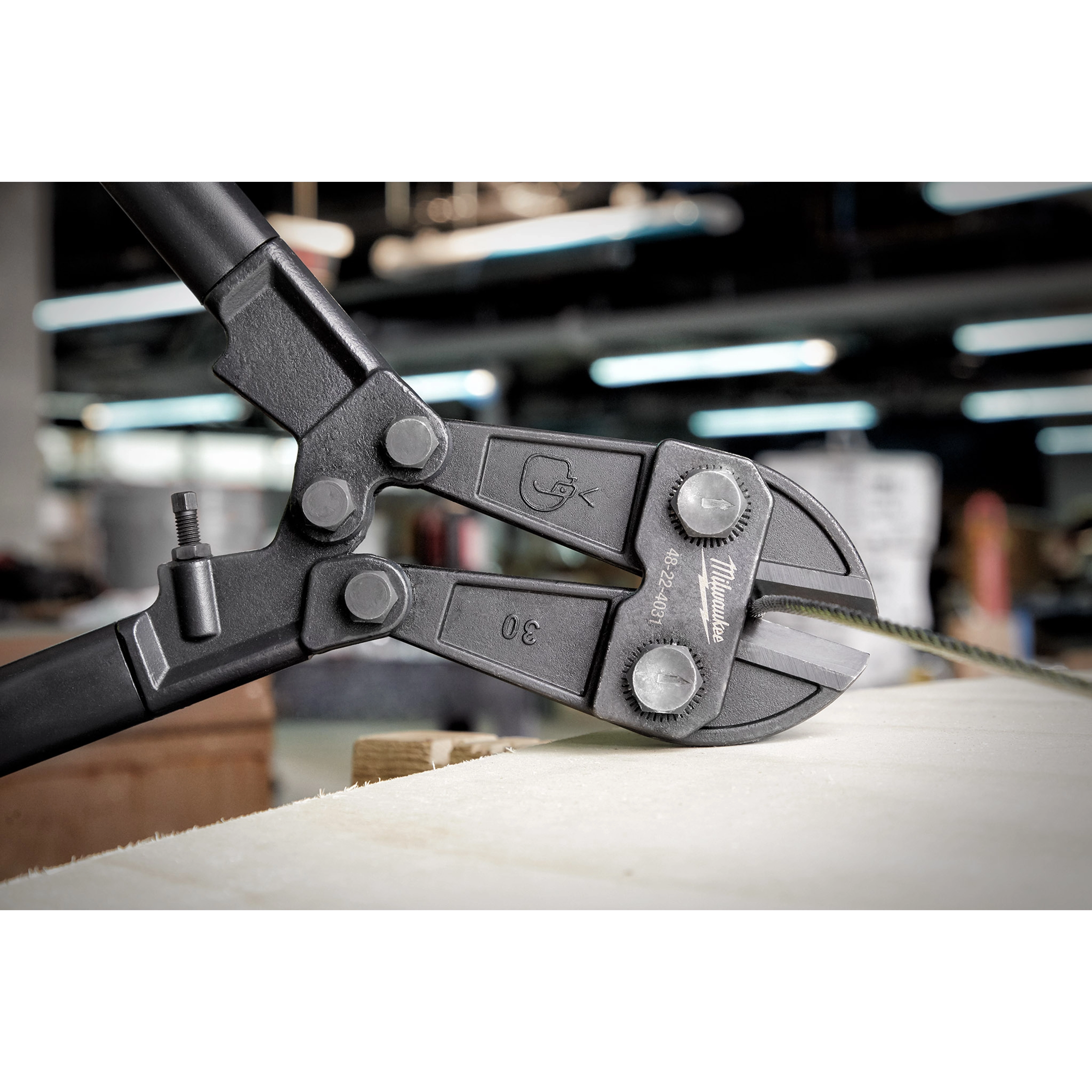 Close-up of a 30" Bolt Cutter cutting a piece of wire, featuring its sharp jaws and sturdy black handles.