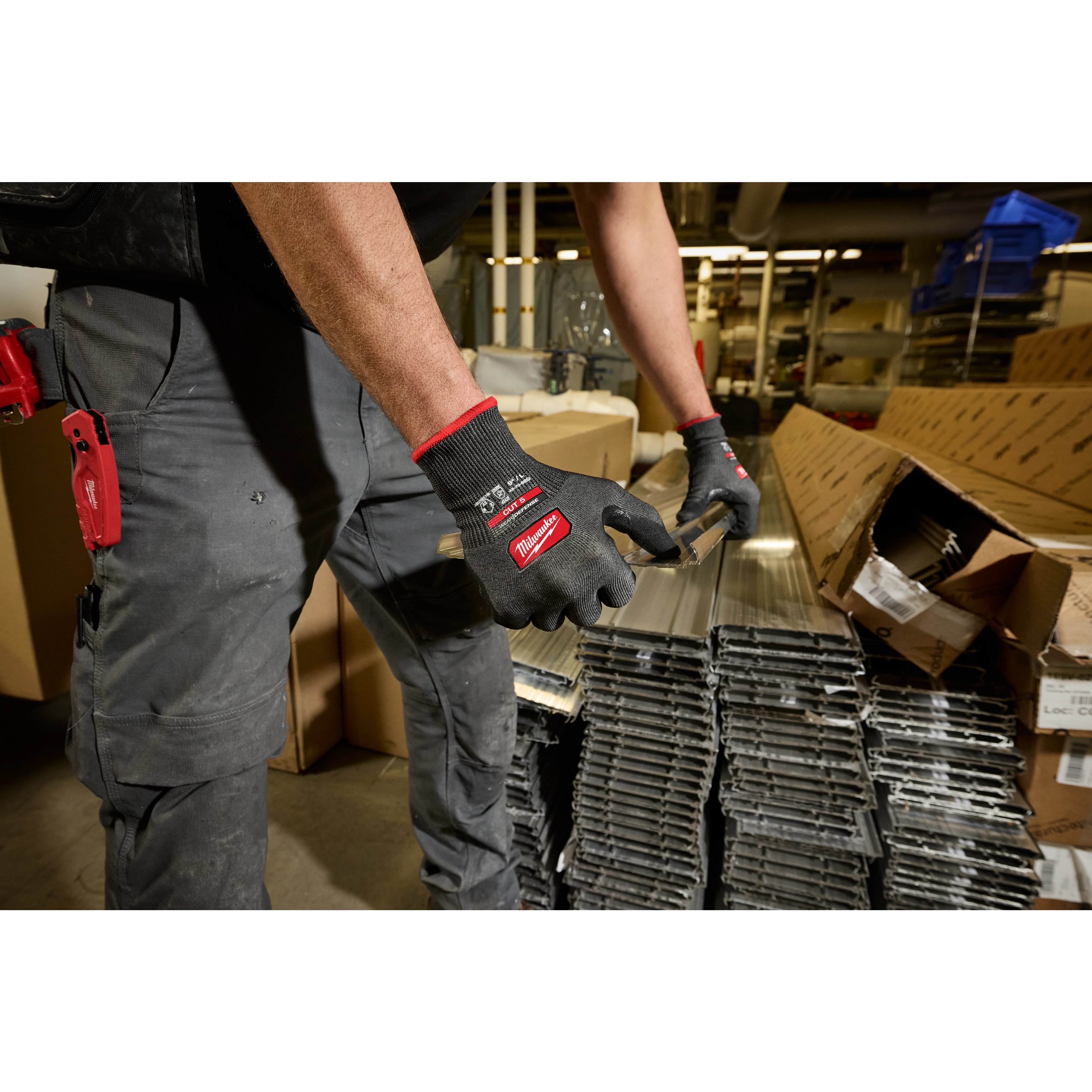 Worker wearing Cut Level 5 High Dexterity Nitrile Dipped Gloves w/ WEAR-DEFENSE Protection handling metal pieces.