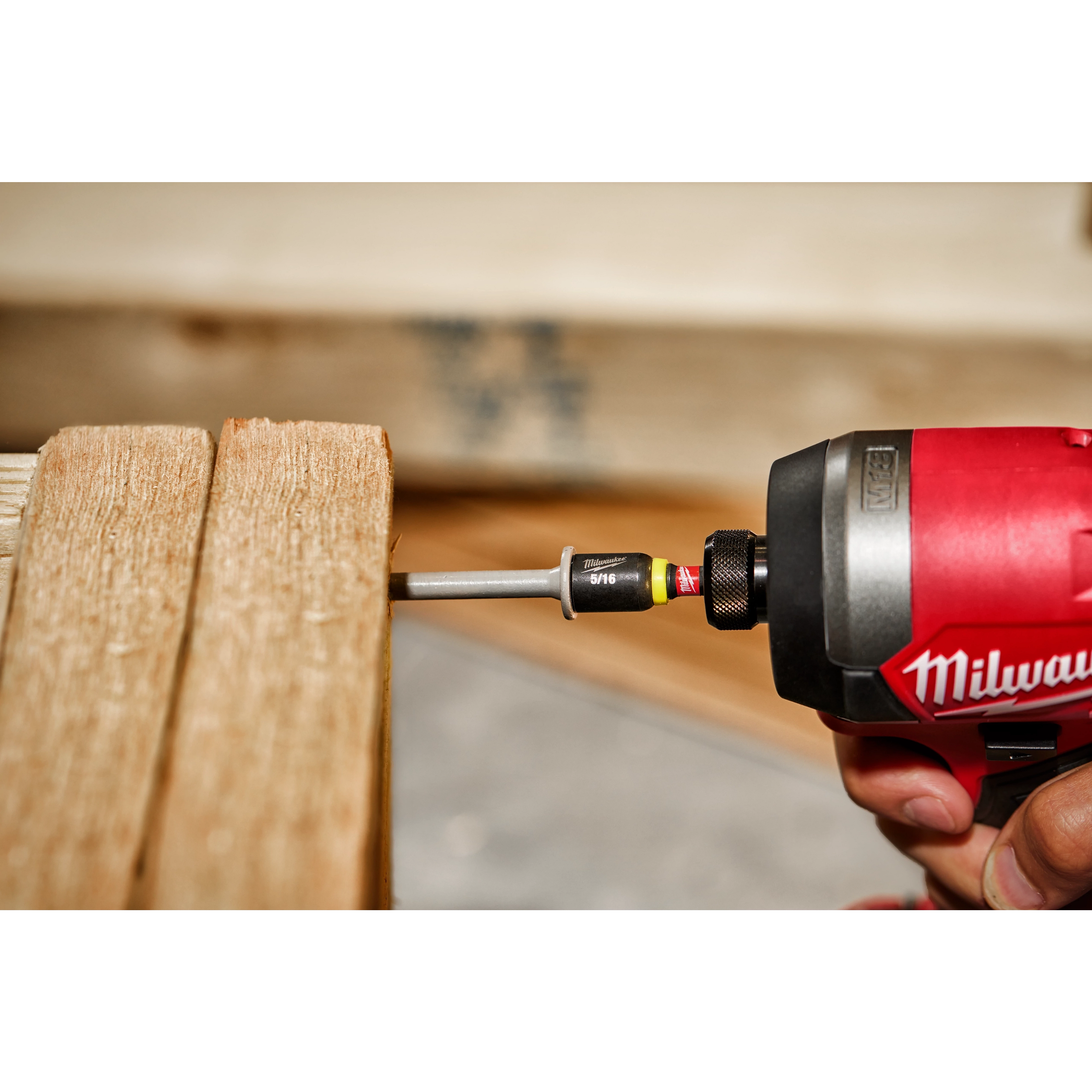 A red power tool using the SHOCKWAVE Impact Duty 5/16" x 1-7/8" Magnetic Nut Driver to screw into wooden planks.