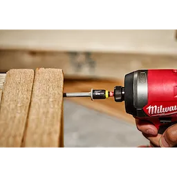 A red power tool using the SHOCKWAVE Impact Duty 5/16" x 1-7/8" Magnetic Nut Driver to screw into wooden planks.