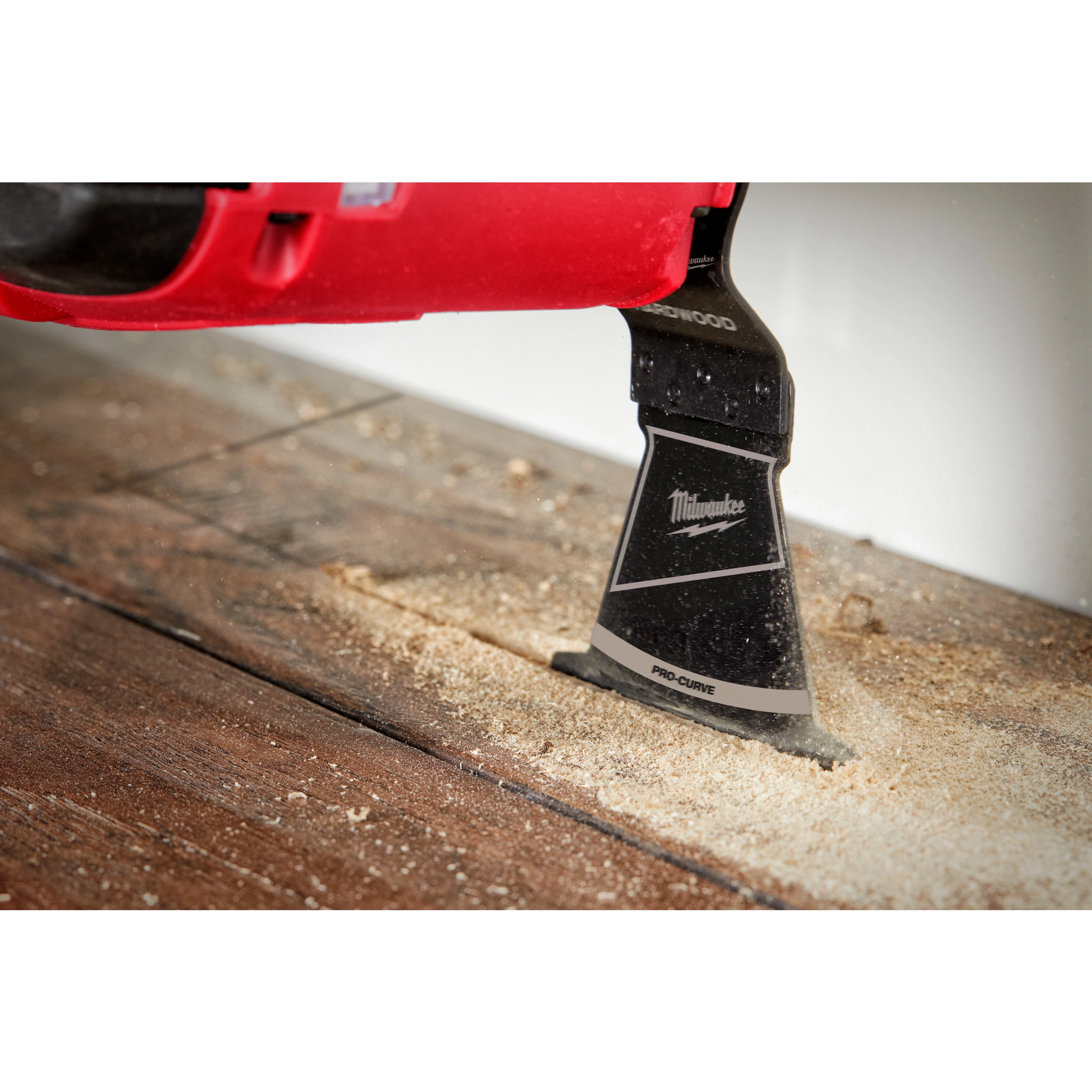 The Milwaukee OPEN-LOK 2-1/2" HCS Japanese Tooth PRO-CURVE Hardwood Multi-Tool Blade cutting through a wooden surface.