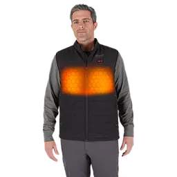 A person is wearing an M12™ Heated AXIS™ Vest over a long-sleeve shirt. The vest has visible heated zones on the chest area, highlighted in orange with a hexagon pattern. The vest is black and features a zip-up front.