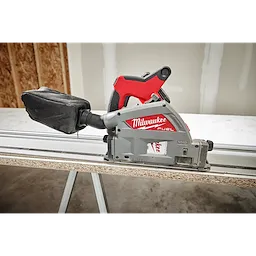 Milwaukee Fuel 6-1/2" 52T Laminate Track Saw cutting a piece of laminated wood on a workbench, with a dust bag attached.