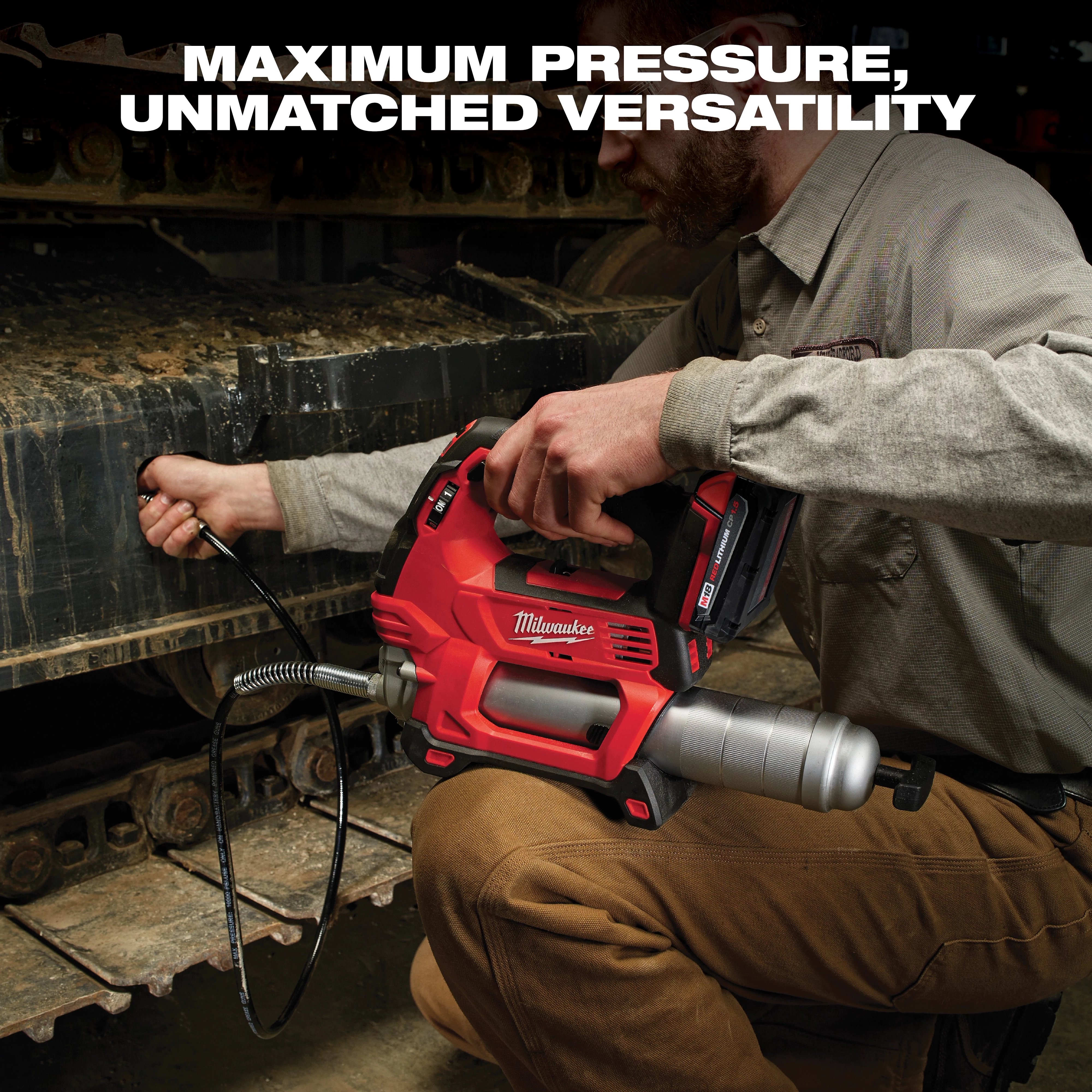 A person using a red Milwaukee cordless grease gun on heavy machinery tracks. The text above reads, "MAXIMUM PRESSURE, UNMATCHED VERSATILITY." The grease gun has a flexible hose and metal barrel, conveying its robust performance.