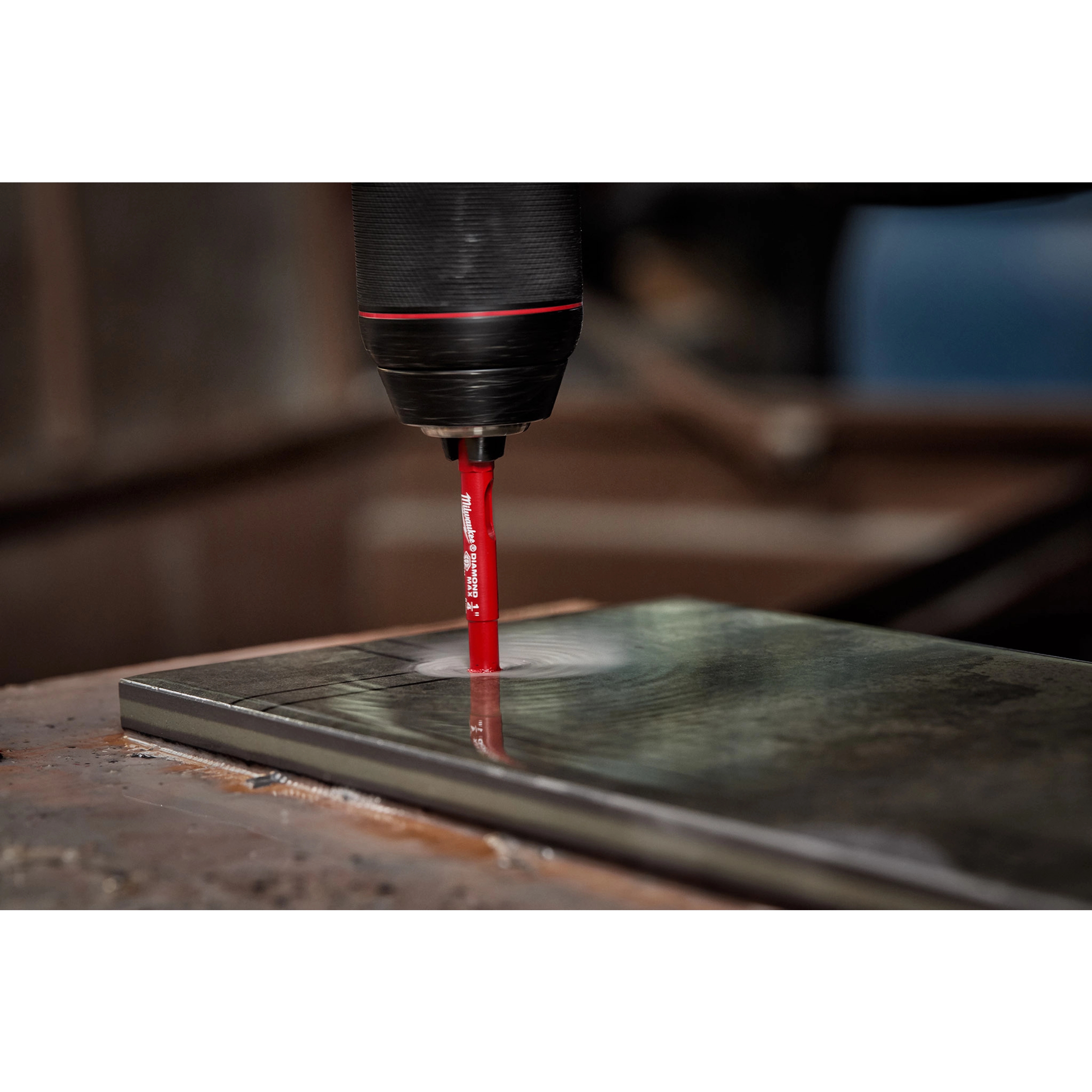 A drilling machine uses a 1/4" Diamond Grit Hole Saw to drill into a rectangular tile, generating a circular hole.