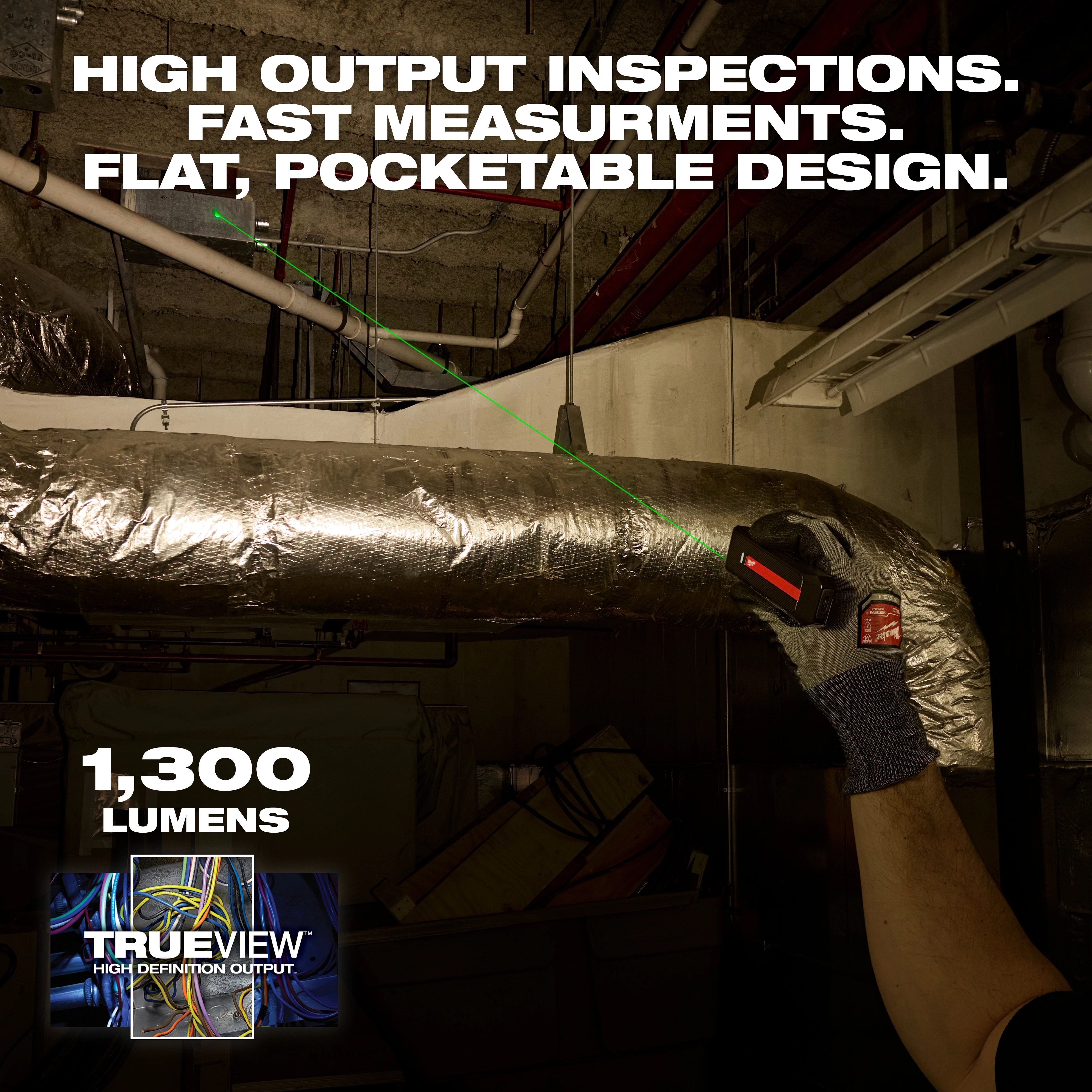Worker aims Milwaukee Rechargeable Flat Flashlight w/ Green Laser at ductwork in a dim industrial space.