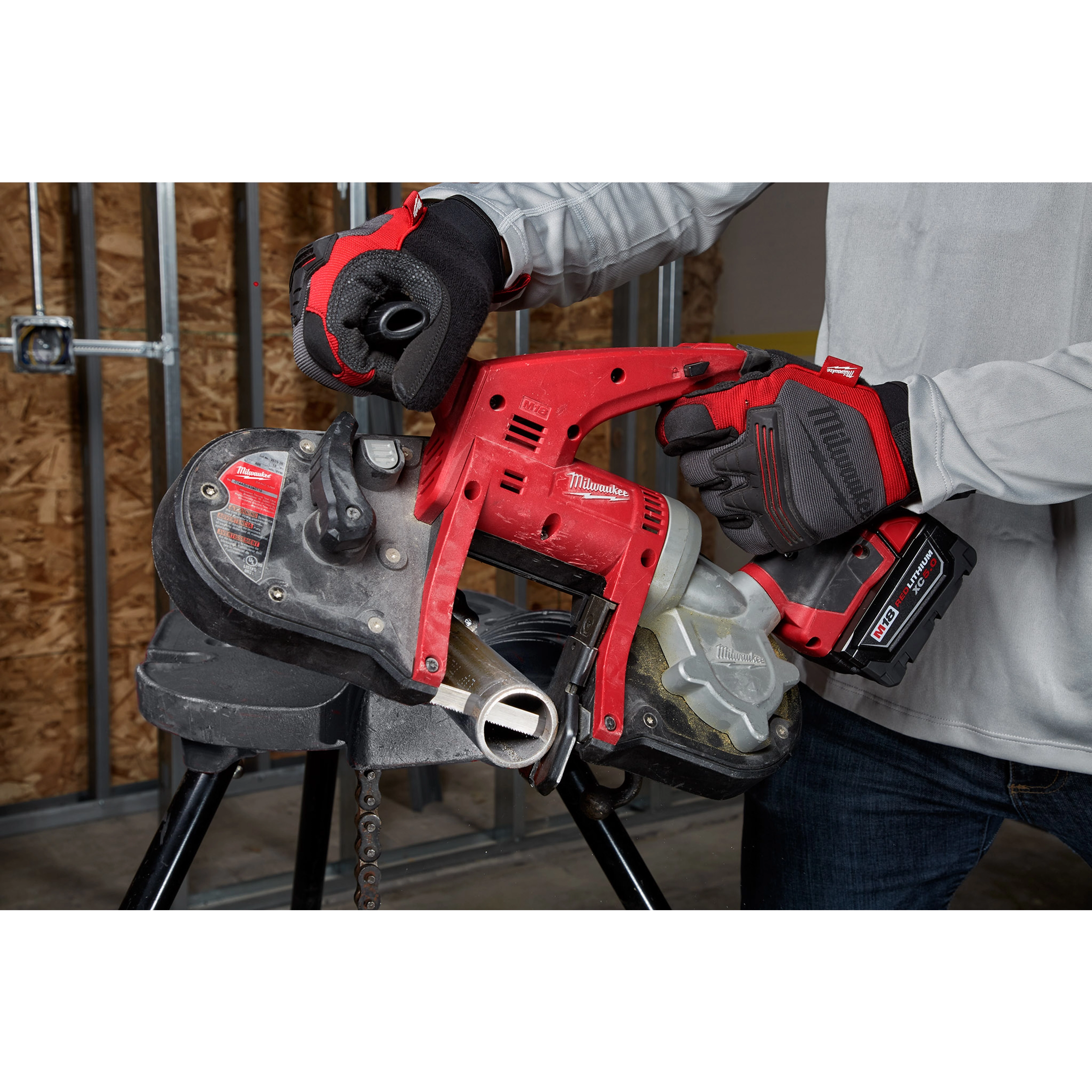Person using a red and black Compact Thick Metal Band Saw Blade to cut metal pipe, wearing red and black gloves.