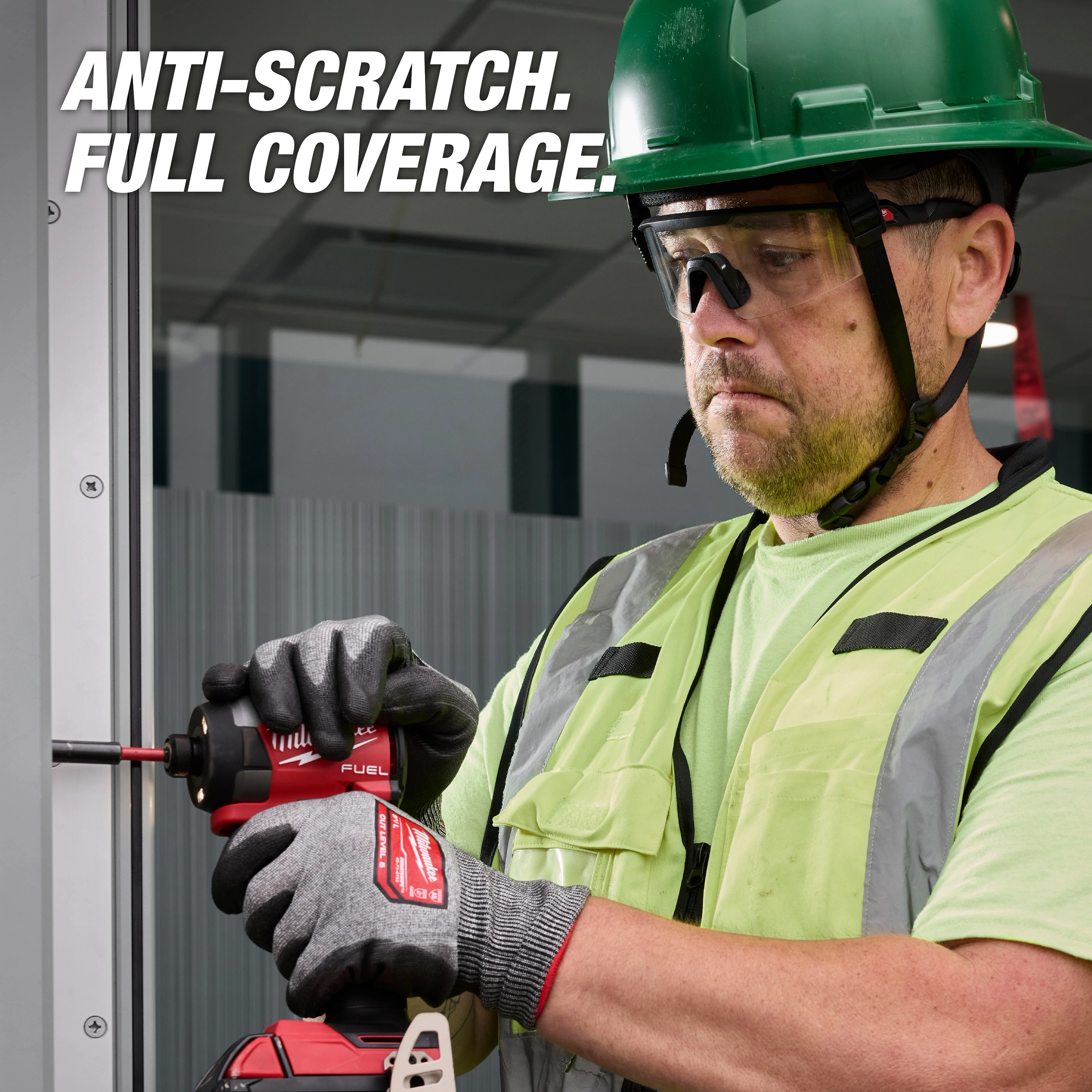 A construction worker wearing Wrap Around Safety Glasses - Clear Anti-Scratch Lenses operates a red power tool, promoting anti-scratch full coverage.