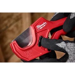 A 1-5/8" ratcheting pipe cutter with a red body is being held by a gloved hand.