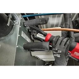 A worker uses the 1/4" - 7/8" Streamline® ACR Pivoting Press Ring Kit for M18™ FORCE LOGIC™ Press Tool to install copper piping in a metallic unit. The worker wears black gloves and operates the red and black press tool, which is clamped onto the copper pipe.
