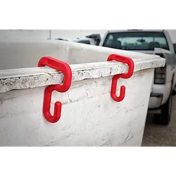Red plastic hooks labeled "3%22%20Bucket%20Hook" are attached to the rim of a large white bin. A pickup truck is in the background.