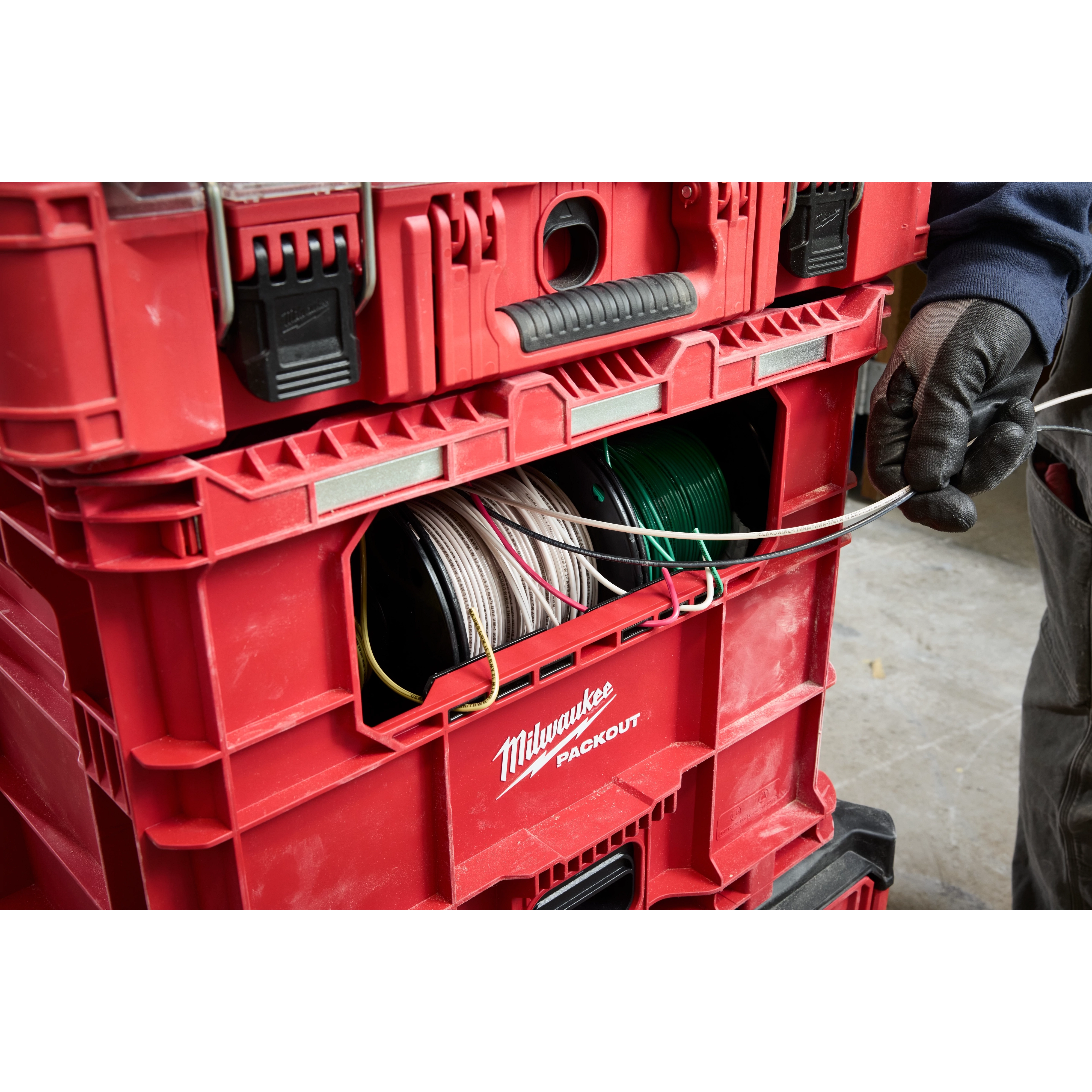 Red PACKOUT Wire Pulling XL Crate holding multiple spools of wire. A gloved hand is pulling a wire from the crate.
