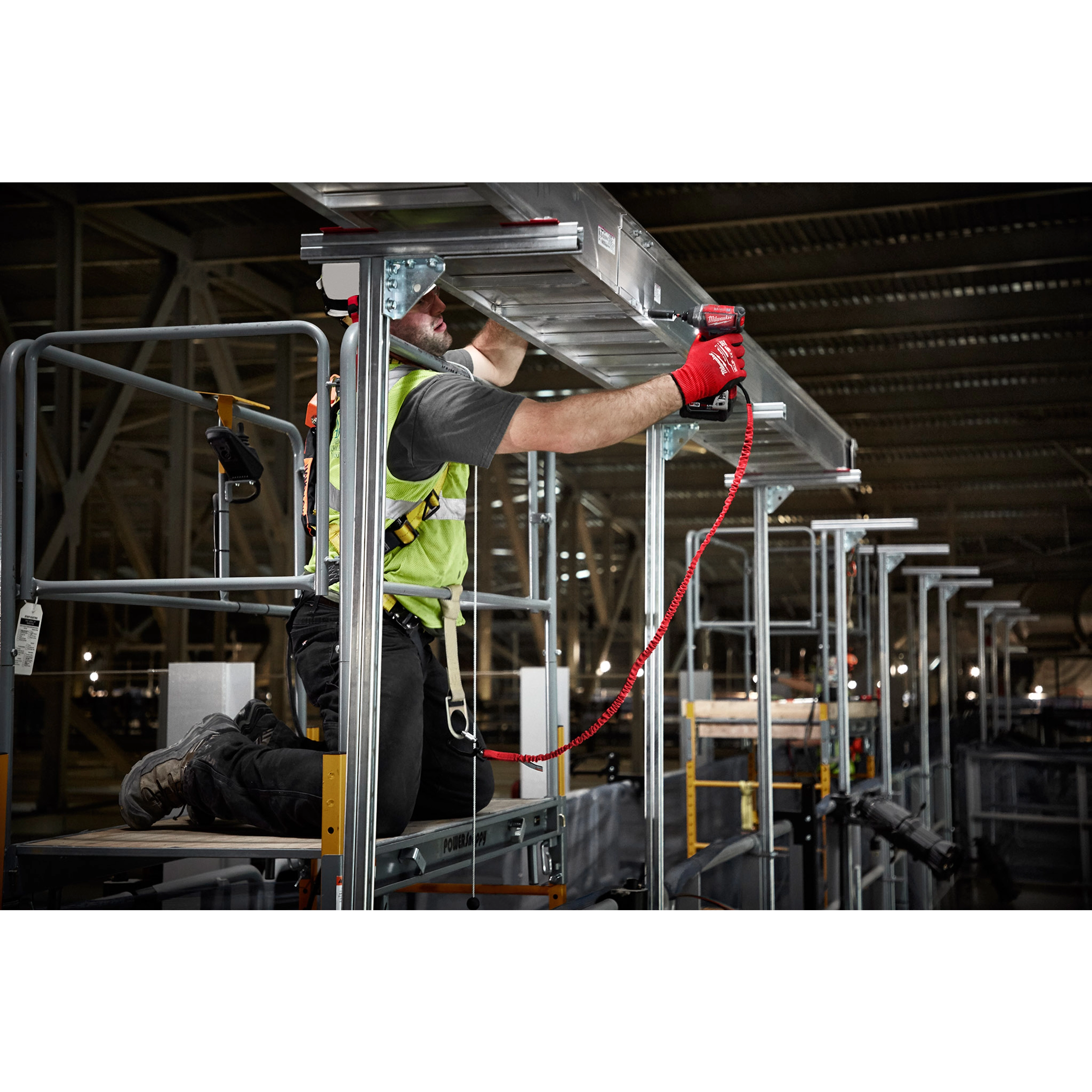 Worker using 10%20LB%20Extended%20Reach%20Locking%20Tool%20Lanyard for safety while operating a power tool at height on scaffolding.