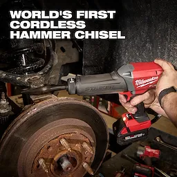 Hand holding an M18 FUEL STRIKER Hammer Chisel near a vehicle brake assembly in a workshop.