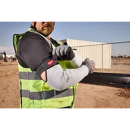 Worker wearing Cut Level 4 Protective Sleeves on a construction site, with a high-visibility vest and gloves.